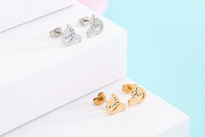 Close-up of cute hollow fox stud earrings in silver and gold metal finishes