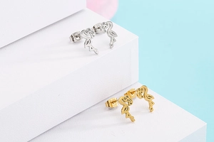 Detail of flamingo stud earrings in silver and gold finish on a display stand
