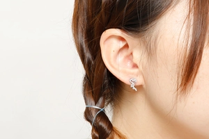 Close-up of a silver flamingo stud earring worn by a model in a natural setting