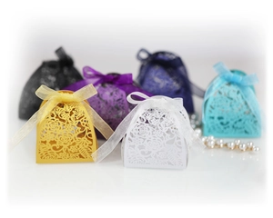 Detail of laser-cut rose hollow candy boxes with silk ribbons in multiple colors