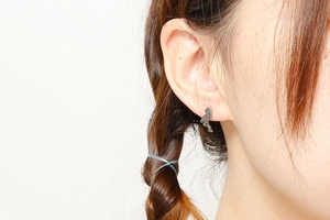 Close-up of a silver flamingo stud earring worn by a model in a minimalist style