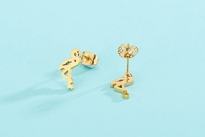 Macro shot of gold flamingo stud earrings in stainless steel on light blue backdrop