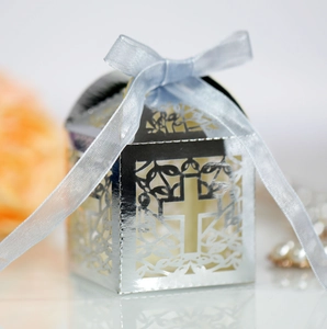Detailed view of silver laser-cut cross favor box with a light blue silk ribbon bow