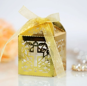 Detail of golden laser-cut wedding favor box with cross pattern and satin ribbon