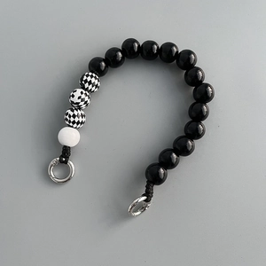 Detail of checkerboard wood beads and black polished beads on a short phone strap