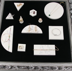 Close-up of golden jewelry collection displayed on marble geometric stands with black velvet