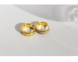 Macro shot of gold plated C-shaped huggie earrings with beige enamel drip oil details