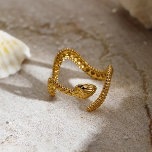 Punk style golden snake open ring with detailed scale texture on a stone background