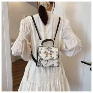 White butterfly pattern backpack with black straps and metallic bow buckle for women