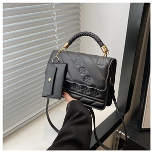 Detail of black PU leather handbag with woven handle and gold-tone metal hardware