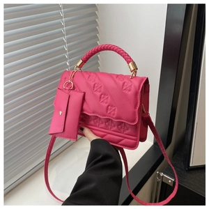 Detail of rose red quilted tote bag featuring a chunky woven handle and mini coin purse
