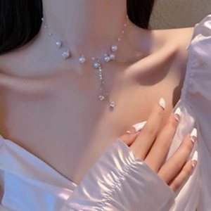 Detail of silver pearl necklace with cubic zirconia pendants worn by a model