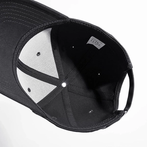 Interior view of black cotton baseball cap showing stitching and 100% cotton wash label