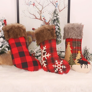 Three plaid Christmas stockings with snowflake and reindeer patterns on a white faux fur rug