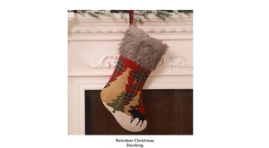 Detailed view of moose and pine tree embroidery on a red and black plaid Christmas stocking