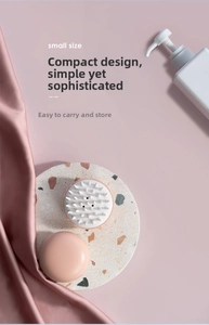 Close-up of pink scalp massager brush with soft silicone bristles and compact design