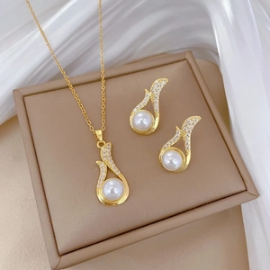 Elegant gold titanium jewelry set with large white pearls and sparkling zircons on silk