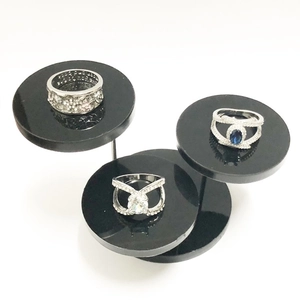 Three-tier black acrylic display stand showcasing silver rings with blue and white stones