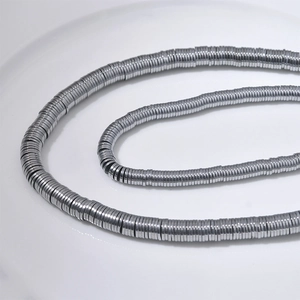 Silberne Hämatit-Perlenkette auf einem weißen Teller mit metallischem Glanz im Fokus