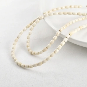 Minimalist cream white rice-shaped stone beads necklace on textured white surface