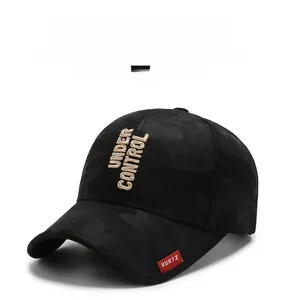 Detail of black camo baseball cap featuring beige Under Control embroidery and red side label