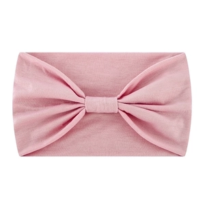 Close-up of pink elastic yoga headband showing soft knit texture and central bow knot