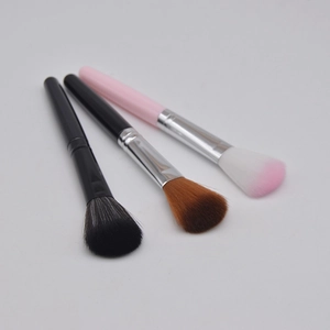 Detailed view of three professional makeup brushes with soft synthetic bristles and sleek handles