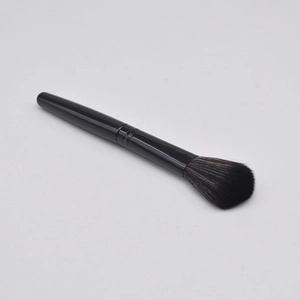 Detail view of professional black handle blush brush on a light grey background
