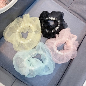 Detail von vier bunten Organza-Haargummis mit Kunstperlen in einer grauen Aufbewahrungsbox