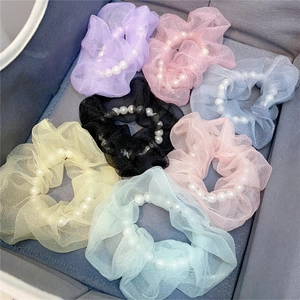 Detail von sieben Organza-Haargummis mit weißen Perlen in verschiedenen Pastellfarben