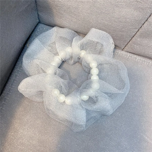 Detailansicht eines weißen Organza-Haargummis mit eleganten Perlenverzierungen