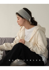 Close-up of a wide grey knitted headband with ribbed texture worn by a model