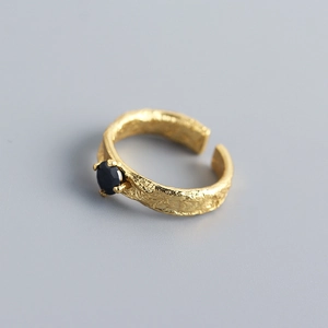 Macro shot of gold-plated silver ring with black zircon stone and tin foil texture detail