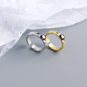 Close-up of S925 silver and gold open rings featuring irregular foil texture and black zircon