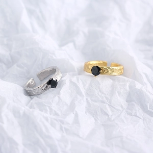 Detail of silver and gold rings with black zircon inlay and unique foil texture finish