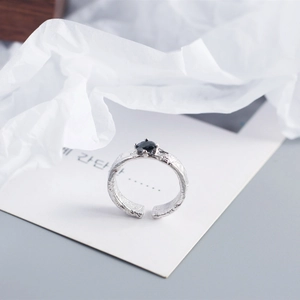 Close-up of silver ring with hammered foil texture and a central black zircon gemstone