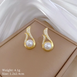 Macro detail of gold earrings with white pearls and diamonds on a brown jewelry box