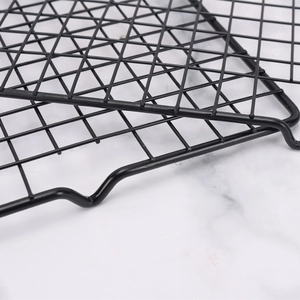 Non-stick black carbon steel cooling rack for baking cakes and bread on marble background
