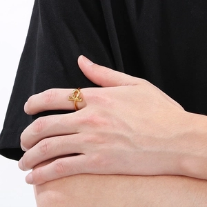 Detailed close-up of a golden Ankh cross ring featuring a polished metallic finish on a model