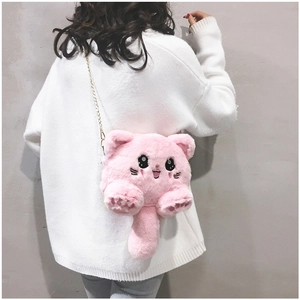 Detail of pink plush cartoon cat bag with golden chain strap worn by a model