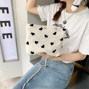 Beige canvas tote bag with black heart patterns and textured fabric in a lifestyle view