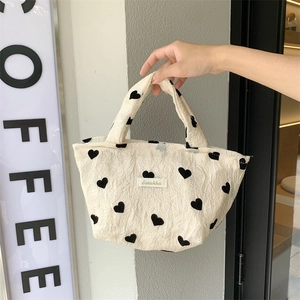 Close-up of heart pattern canvas tote bag with textured fabric and woven label detail