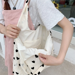Detail view of the cream canvas tote with black heart print and zippered inner pocket