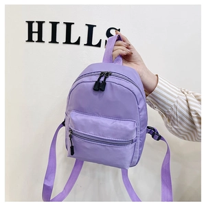Close-up of purple nylon mini backpack held by hand featuring front zipper pocket