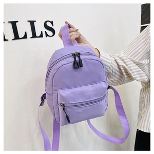 Close-up of a purple nylon backpack featuring black zippers and durable webbing handles