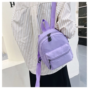 Rear view of a model wearing a mini purple nylon backpack with adjustable straps