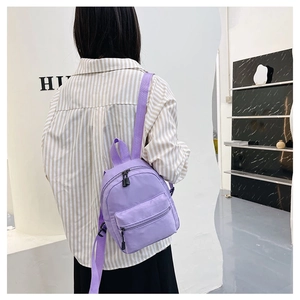Detail of a purple nylon mini backpack with adjustable straps worn by a model