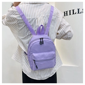Detailed back view of a purple nylon mini backpack with adjustable straps on a model