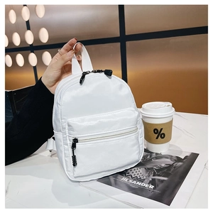 Classic white nylon backpack shown in a modern cafe setting with stylish accessories