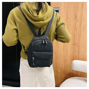 Rear view of a black nylon backpack on a model wearing a lime green knit sweater